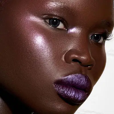 Model wears shimmering makeup look with purple lips