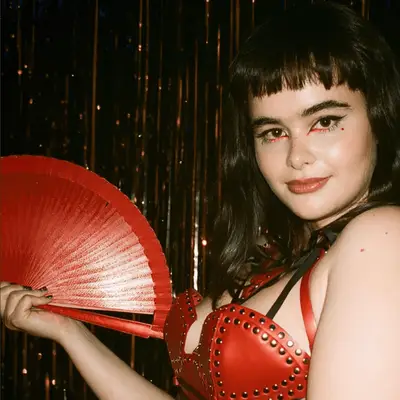 barbie ferrera holding a red fan wearing a euphoria makeup look
