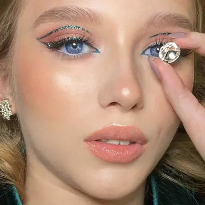 Woman wears teal glitter double winged cut crease eyeliner