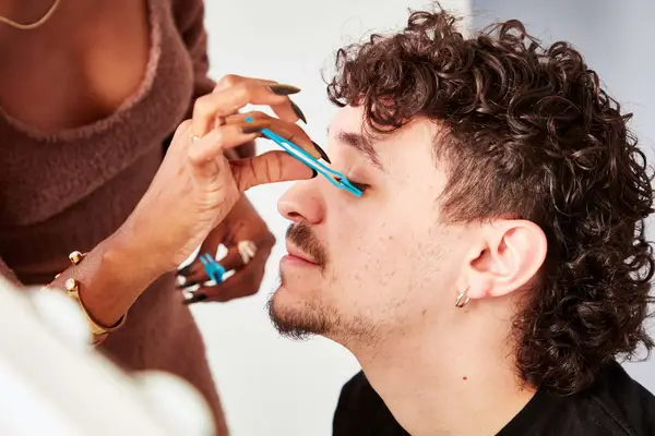 Person applying Lilly Lashes Clear Brush-On Lash Adhesive and lashes to their eyes