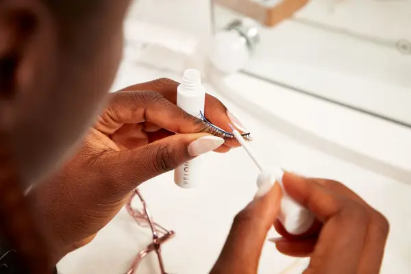Hands applying lash adhesive to Velour Second Nature Plant Fibre Lashes against white counter
