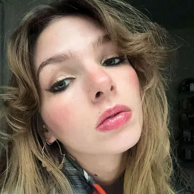 MYM Beauty editor Ali Webb wears a neutral makeup look with gold glitter, cherry tinted lip gloss, and blush