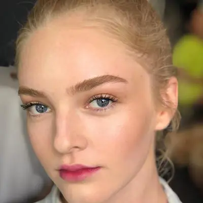 Model wears blended pink lip stain and natural lashes