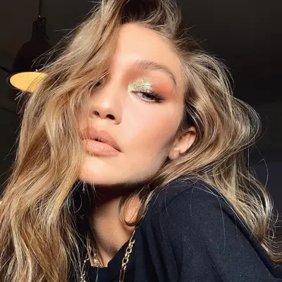 Gigi Hadid wears an iridescent sparkly eye makeup look and voluminous waves