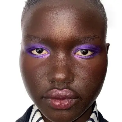 Model with purple jewel-toned eyeshadow and subtle berry lip