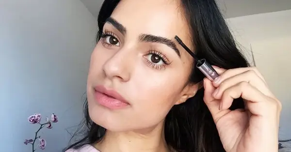 woman with thick eyebrows applying eyebrow gel