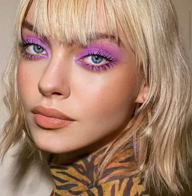 model wears vivid violet eyeshadow on top and bottom lashline and eyelids