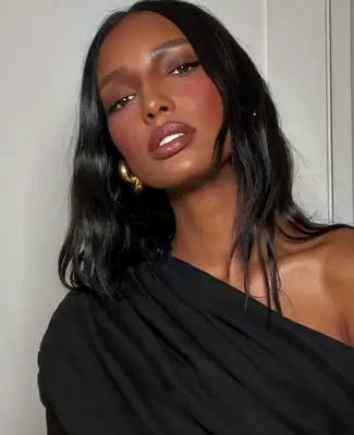 Jasmine Tookes wears berry toned blush and lipstick with chocolate brown eyeshadow on eyelids