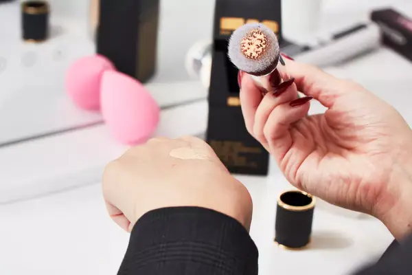 Close up of a person dabbing a beauty brush with Pat McGrath Labs Skin Fetish Sublime Perfection Foundation on the back of their hand