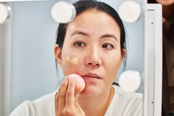 Person applying Charlotte Tilbury Airbrush Flawless Foundation to their skin with a beauty blender