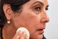 Person applying Estée Lauder Double Wear Stay In Place Matte Powder Foundation to their jaw with a makeup sponge