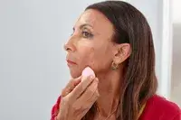 Person using a makeup sponge to apply foundation to their face