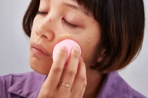 Person applying foundation with a beauty blender to their cheek
