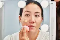 Person applying Charlotte Tilbury Airbrush Flawless Foundation to their skin with a beauty blender