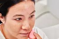 Person applying Charlotte Tilbury Airbrush Flawless Foundation on their face with a beauty blender