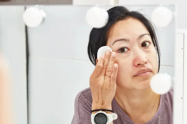 Person applying micellar water to their face with cotton round