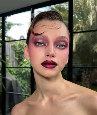 model wears a bold pink makeup look with dark pink frosted and metallic lips