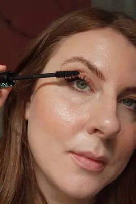 model applying mascara to eyelashes