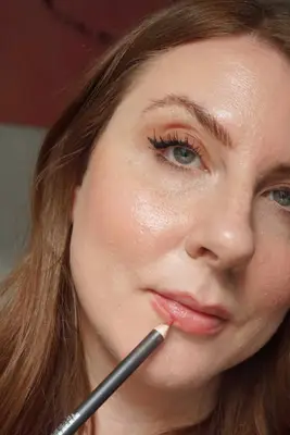 model is applying lipliner to lips