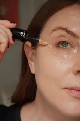 woman applies concealer using a concealer wand under the eyes in 4 small dots