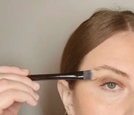 makeup artist applies concealer for brows