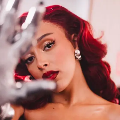 Doja Cat with red hair, glossy eyelids, and a red lip