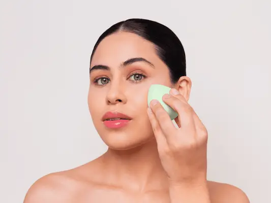 A woman applying foundation with a sponge applicator