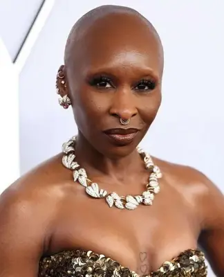 Cynthia Erivo wears a smoky eyeshadow look with prominent false eyelashes and deep crimson red lip