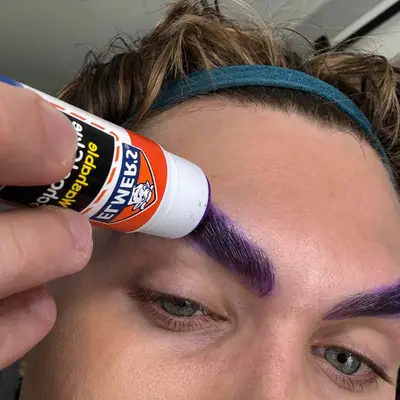 Cristopher glues down brows.