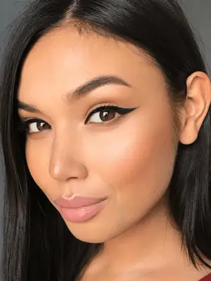 Model wears black liquid winged eyeliner and soft complexion makeup