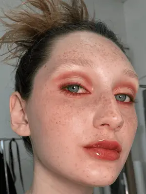 model wears burnt orange shadow and eye liner applied prominently in the crease