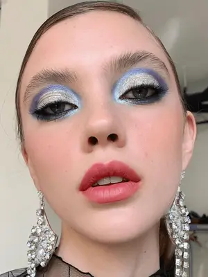 model wears a 60s eyeshadow makeup look with metallic light blue, silver and purple