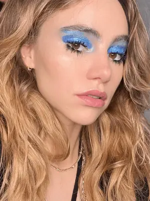Suki Waterhouse wears sparkling blue eyeshadow in cobalt and light blue colors with pronounced lashes