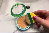 A person uses a makeup sponge to apply Physicians Formula Murumuru Butter Bronzer