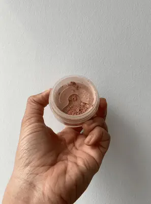 Hand holding a container of bareMinerals Original Loose Powder Foundation SPF 15
