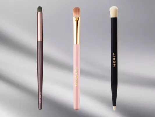 A collage of three eyeshadow brushes from Charlotte Tilbury, Rare Beauty, and Merit