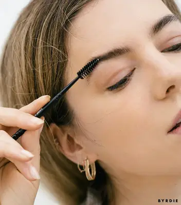 MYM Beauty editor combing eyebrows with spoolie brush