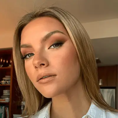 Woman with blonde hair, brown smokey eye, and bright bottom eyeliner