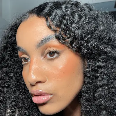 Woman with dark curly hair and natural glowy makeup