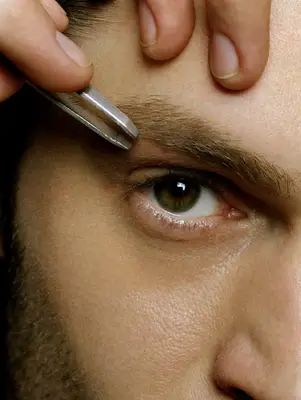 Man tweezing eyebrows