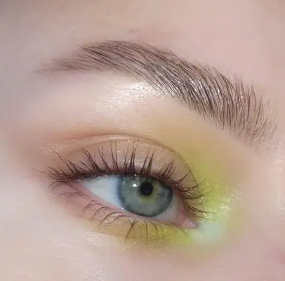 blue eye wearing soft neon green eyeshadow in the corner