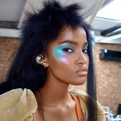 model is wearing an 80s inspired bold neon eye makeup look