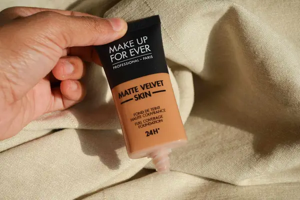 Hand holding an uncapped tube of Make Up For Ever Matte Velvet Skin Full Coverage Foundation