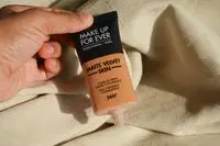 Hand holding an uncapped tube of Make Up For Ever Matte Velvet Skin Full Coverage Foundation