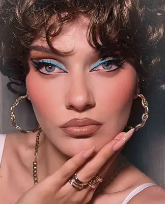 Model is wearing an abstract black and powder blue eyeliner look in a visible wing shape