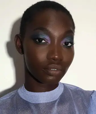 Model is wearing a purple and dark teal metallic eyeshadow look