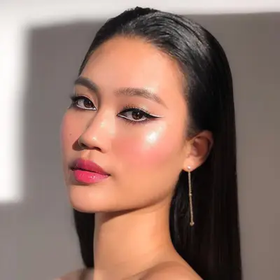 Model with a high contrast black and white reverse eye makeup look and pink lipstick