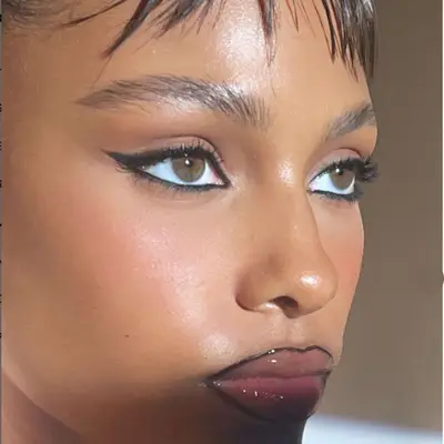 Black smudged cat-eye with glossy lips lined in black.