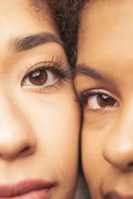 two women with long eyelashes looking at camera