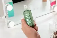 Person holding a bottle of Milk Makeup Hydro Grip Hydrating Makeup Primer in front of a mirror